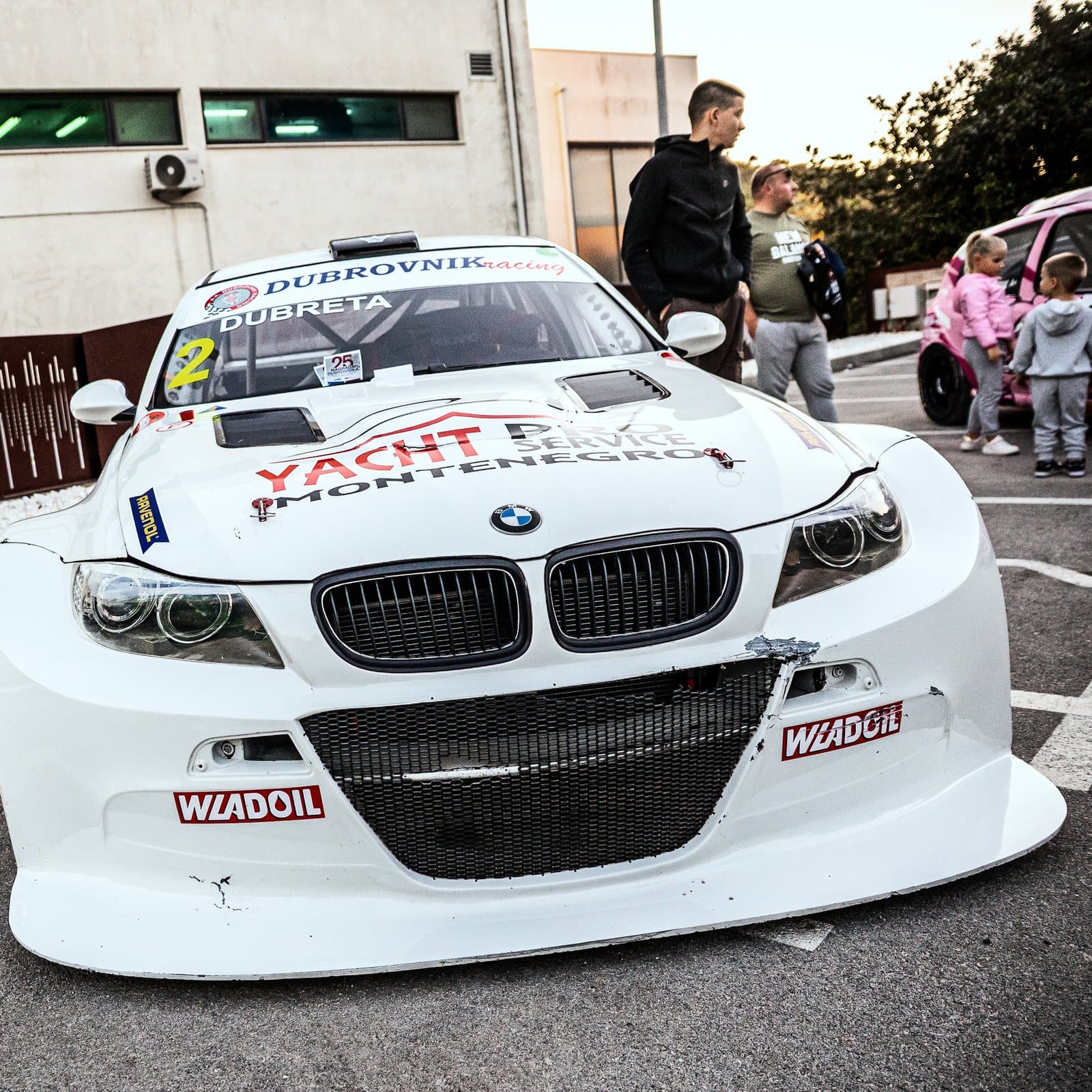 A white BMW race car among visitors in Lapad