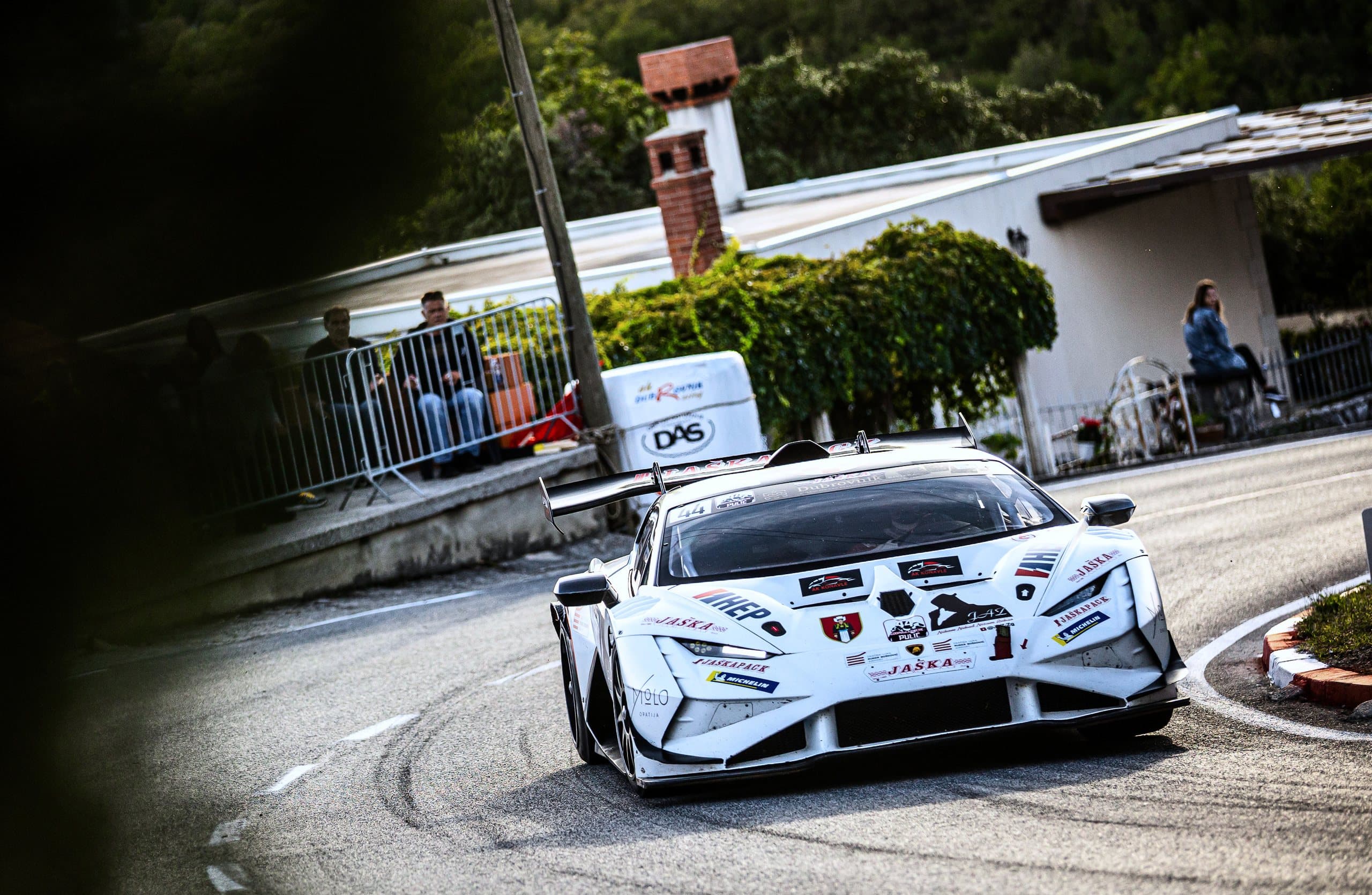 The white Lamborghini no. 44 through a tight bend past the houses
