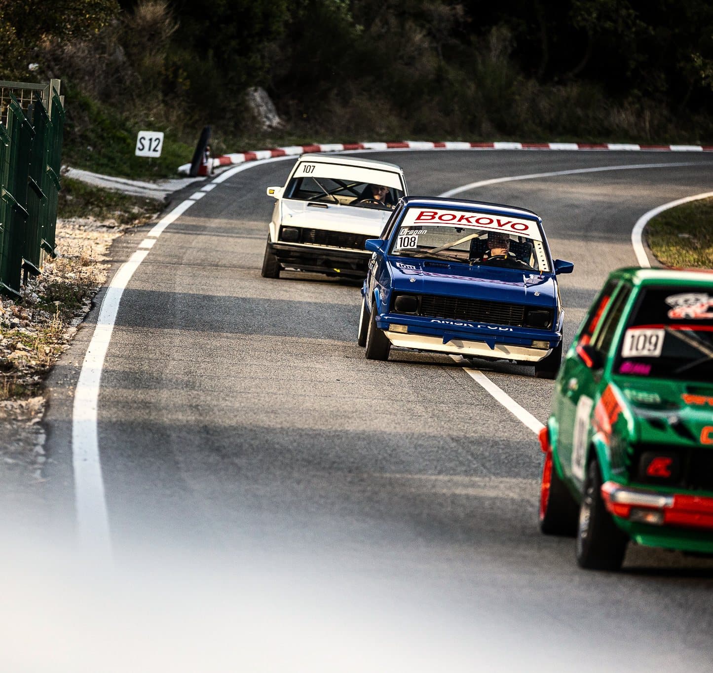Three classic cars nose to tail through a chicane