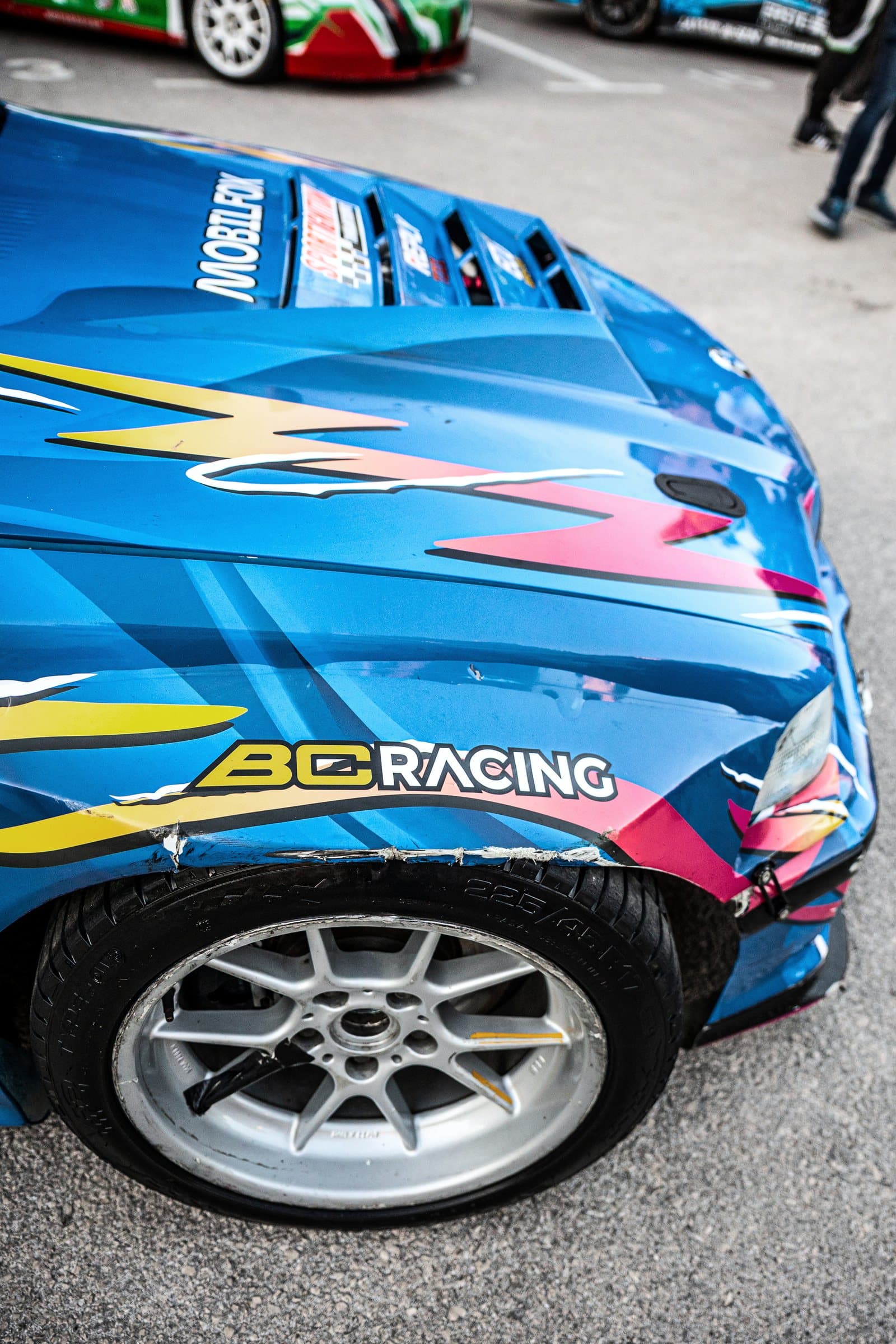 The front wheel and wing of a blue drift car