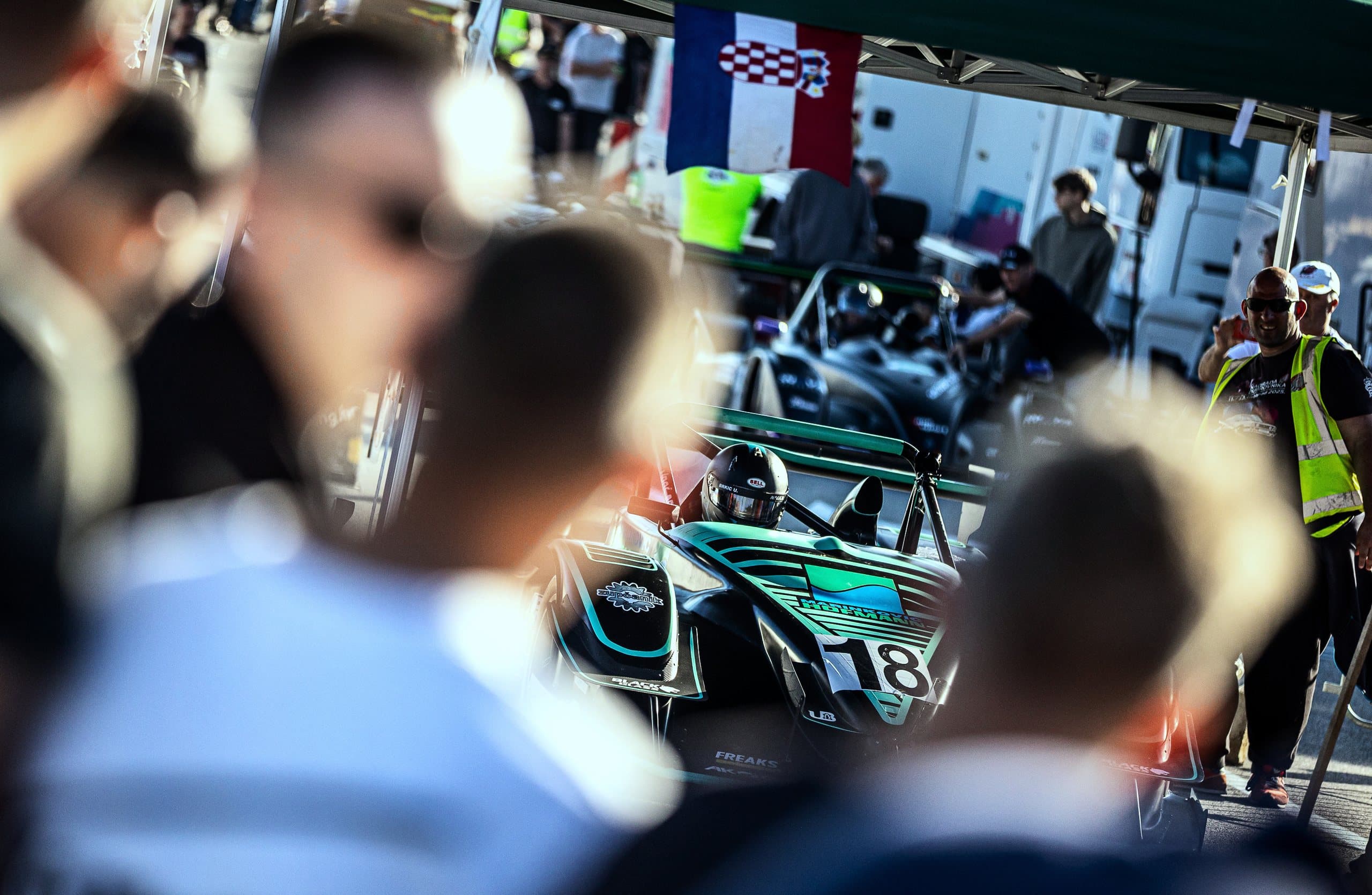Spectators by the start, the green prototype no. 18 behind them